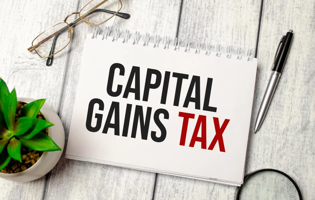 image of capital gains tax words notebook pen glasses magnifier